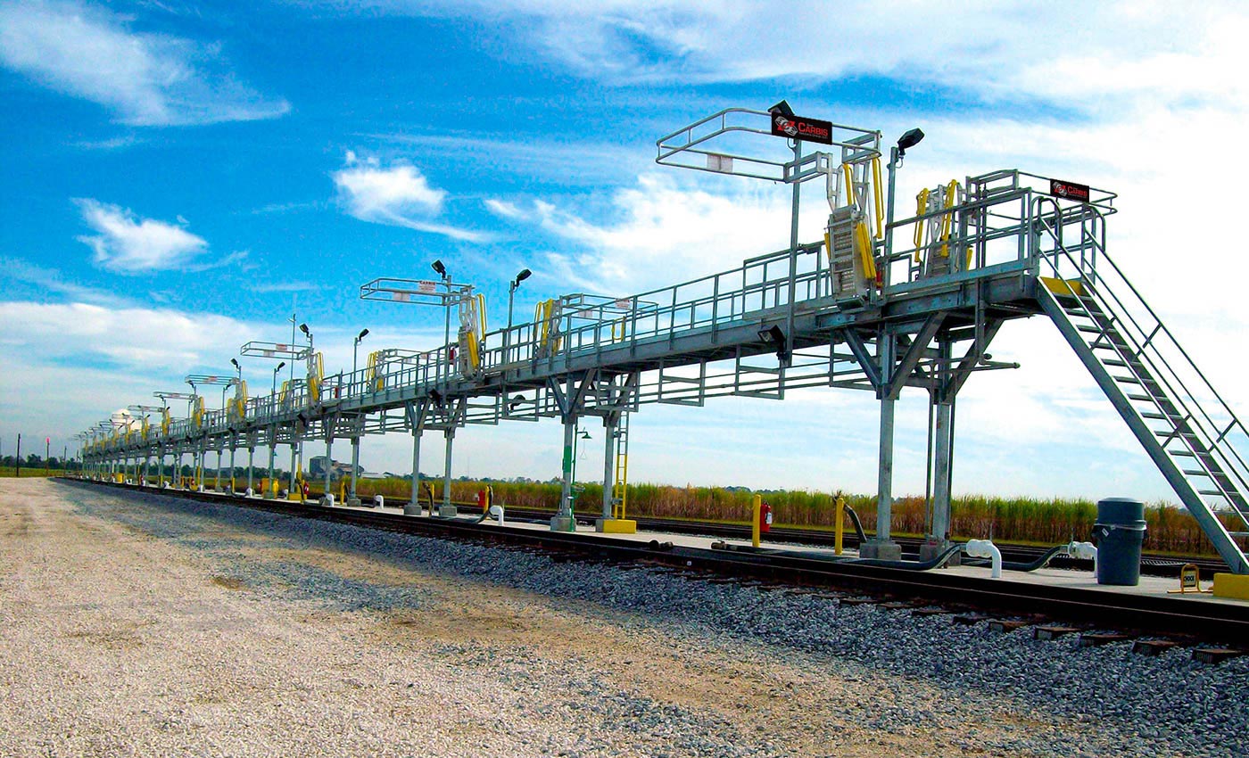 a row of multi hatch bays stands empty in the middle of two train tracks.