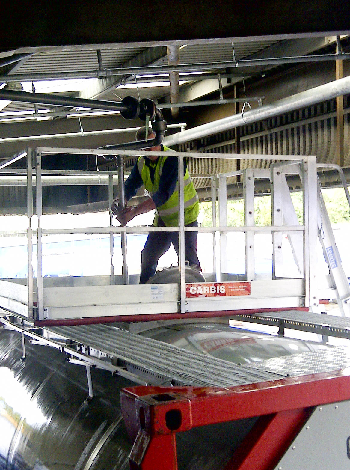 A worker is on top of a Carbis portable tanker truck access system.