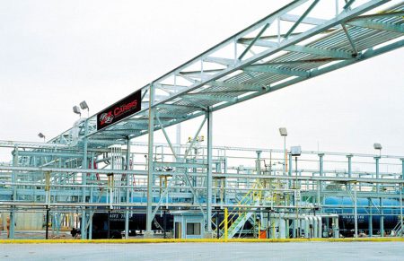 A Carbis solutions pipe rack extends over an asphalt area where trucks can come load fuel.