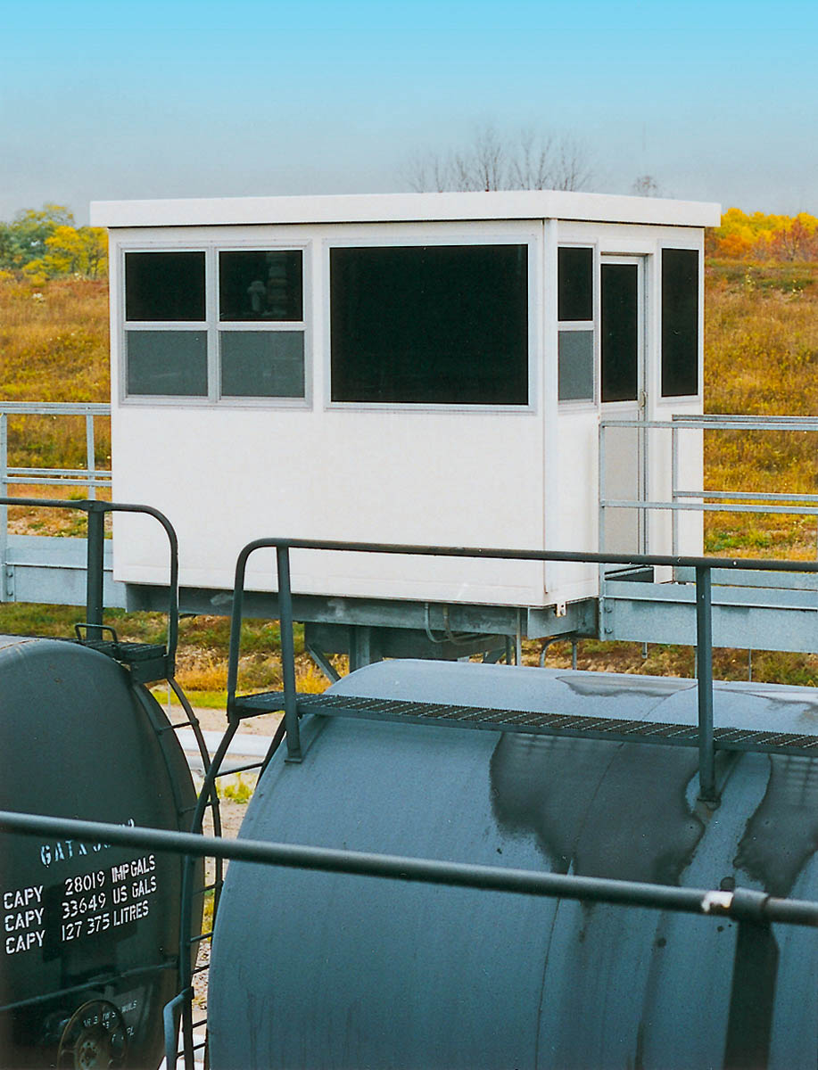 An industrial operator shack near a railroad track.