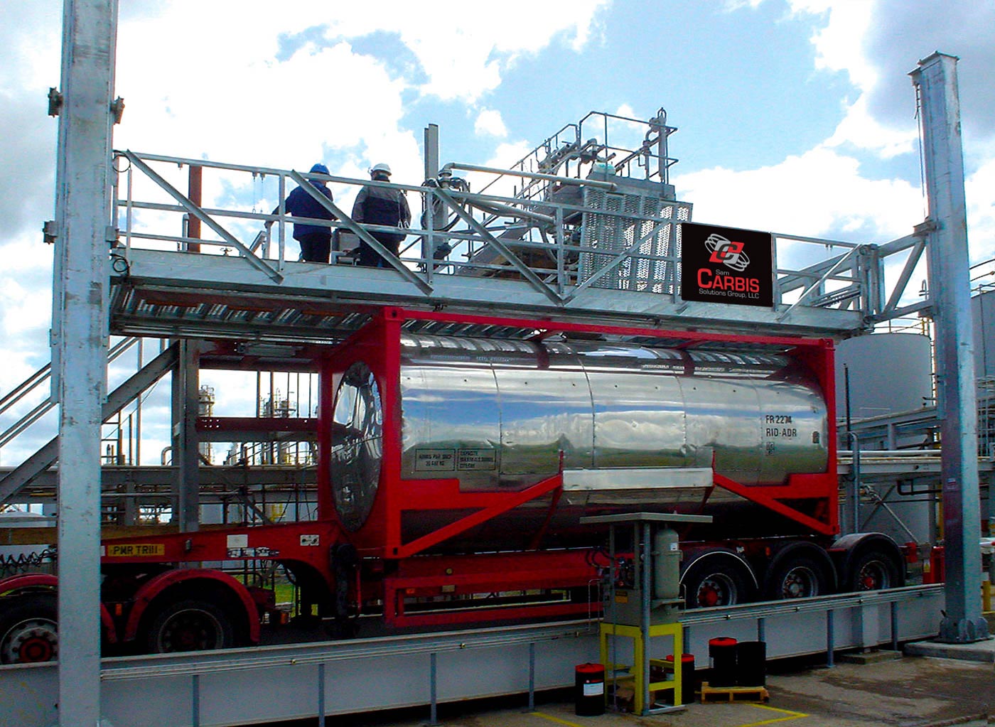 Two men stand on a Carbis Solutions elevated truck platform above a tank truck.