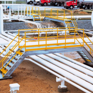 An OSHA Compliant Crossover traverses a series of pipes in an industrial setting.