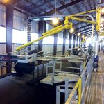 Two Carbis Solutions top loading arms are positioned above tanker railcars to load them.