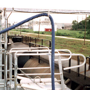 Hose handlers hold a hose over rail cars in a loading station.