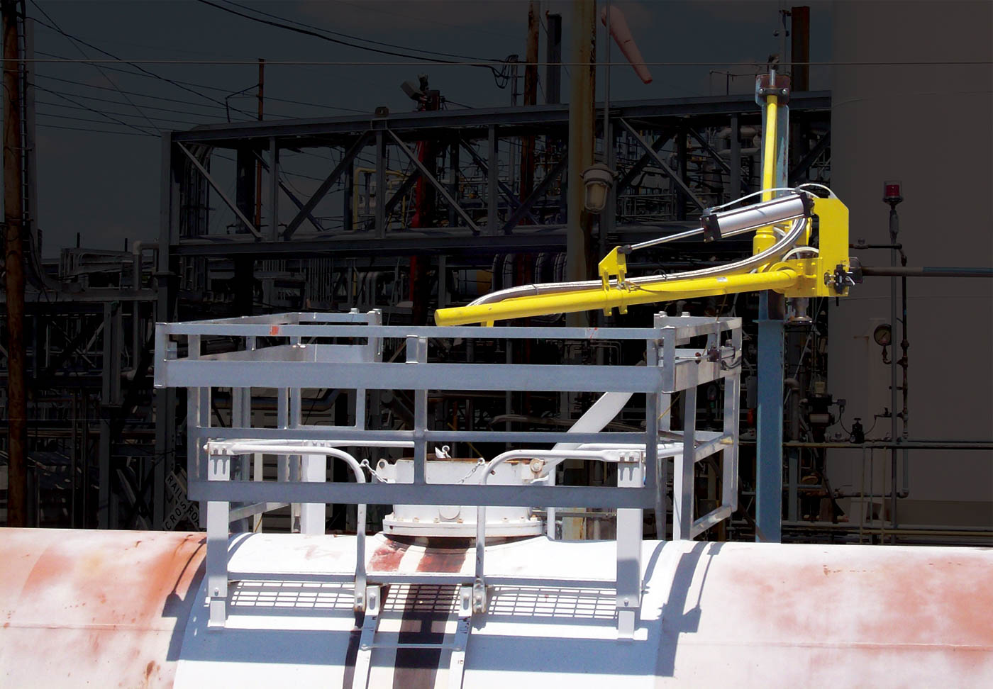 A top loading arm is shown with a safety cage over the top of a tanker railcar.