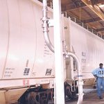 A pellet dry good loading arm is attached to the bottom of a hopper railcar.