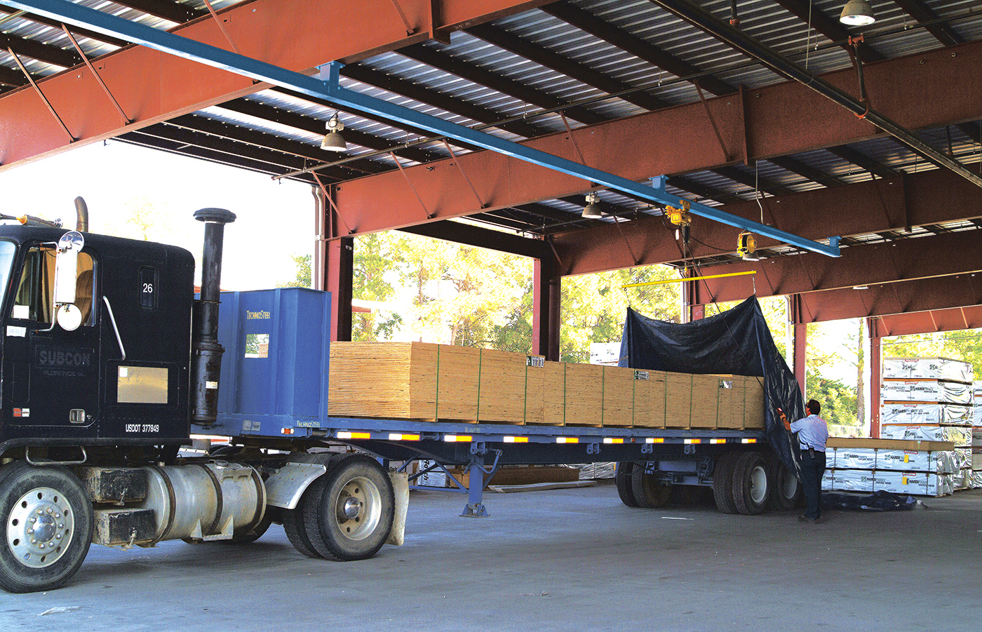 A truck's load is being tarped with an overhead tarping solution.