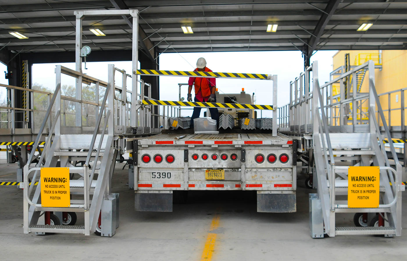 A man works to tarp a flatbed load down at the tarping dock.