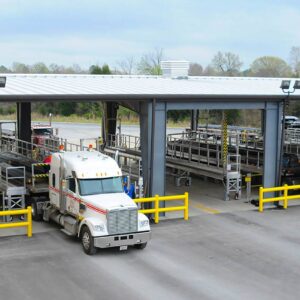 A flatbed tarping dock with several stalls and a loaded 18 wheeler being tarped.