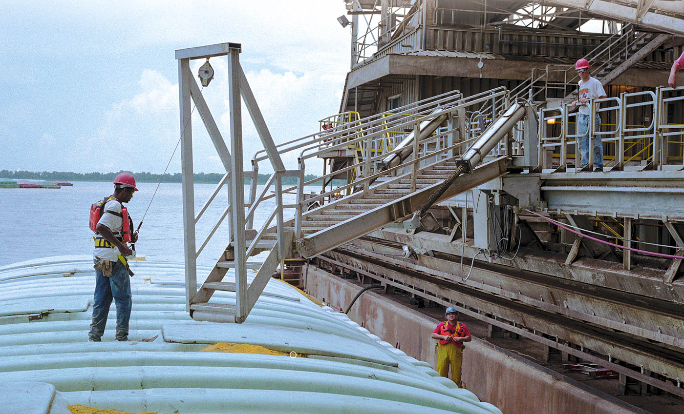 A telescoping marine gangway extends from a ship to a barge.