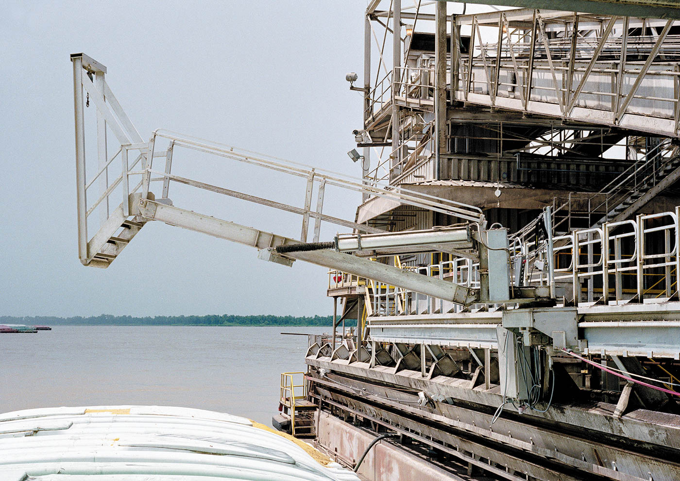 A telescoping marine gangway extends from a ship to a barge.